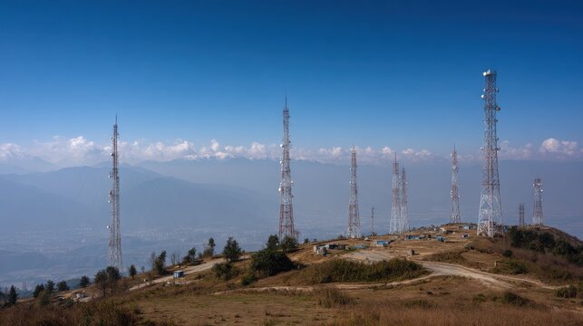 Towering microwave transmission towers stretch across a scenic mountain landscape under a clear blue sky