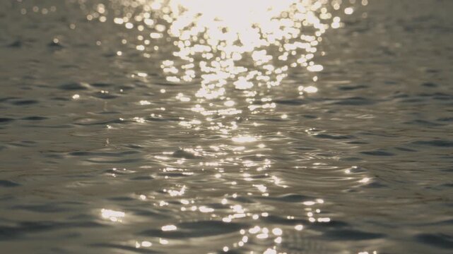 Slow motion abstract water texture with bright sun reflections and smooth flowing movement