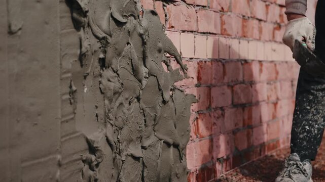 Applying plaster onto brick wall surface with trowel during masonry work