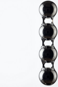 Four obsidian-toned glass spheres align vertically along the right edge of a stark white field, their polished surfaces catching subtle specular highlights and dark internal refractions.