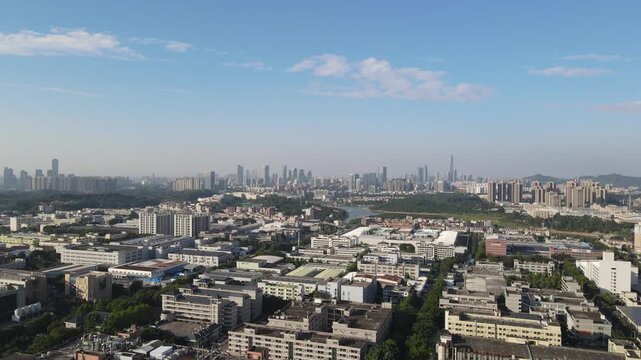 Aerial view of the sprawling industrial landscape and modern city skyline under a clear blue sky in Dongguan, Guangdong Province, China.