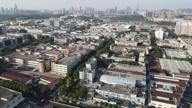 Aerial view of industrial buildings and manufacturing facilities with green trees and urban sprawl in Dongguan, Guangdong Province, China.