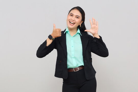 A young Asian woman stands smiling looking at the camera, raising her hand and showing six fingers explaining rules, numbers, or steps, isolated on a white background.