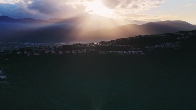 Dramatic sunrays breaking through dark clouds over a silhouetted mountain range.