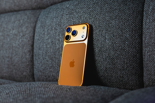 KYIV, UKRAINE - April 20, 2026 : Apple iPhone 17 Pro in Cosmic Orange color with magnetic charger on gray textile sofa.
