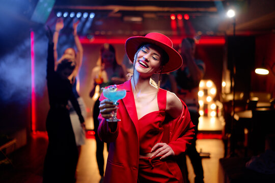Party and celebration. Happy smiling young woman drinking cocktail having fun at the night club
