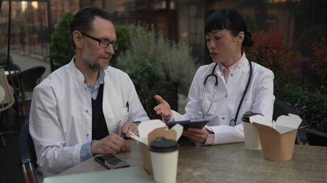 Two doctors discussing patient case during lunch break