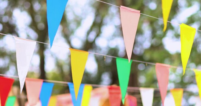 Colorful pennant flags hanging outdoors, gently swaying to create a festive, cheerful atmosphere. Perfect for celebrations, parties, and outdoor events