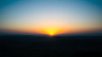 Fototapeta premium Golden rays of dawn breaking over the horizon into a deep blue pre-dawn sky.