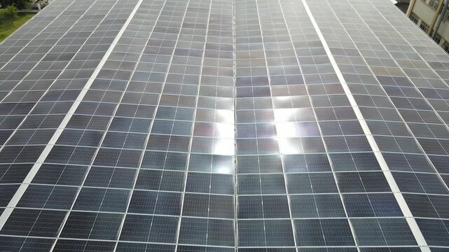 Aerial view of solar panel array with sunlight reflecting on the dark blue surface in Dongguan, Guangdong Province, China.