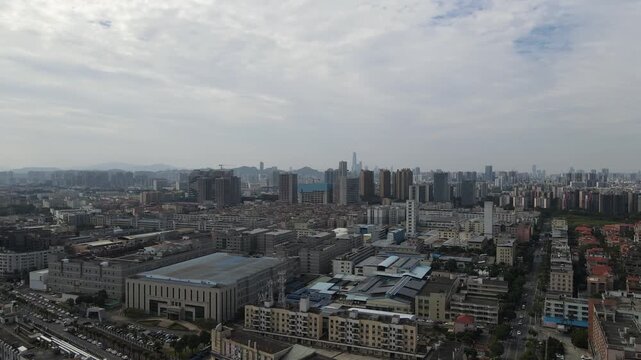 Aerial view of industrial complexes and residential blocks with a distant city skyline under a hazy sky in Dongguan, Guangdong Province, China.