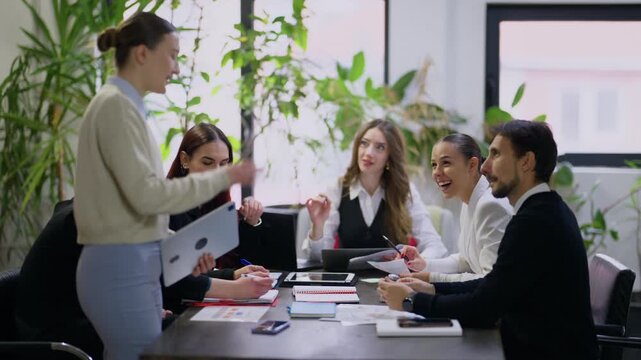 A diverse group of business professionals engages in a collaborative meeting within a contemporary office setting. Young colleagues brainstorm ideas and discuss strategies around a conference table.