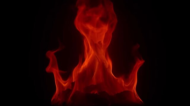 Vibrant red and orange flames leap and dance against a dark black background, creating a dramatic and dynamic fire effect suitable for video backgrounds and motion graphics.