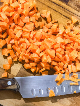 Cubes of carrot, on a wooden cutboard.