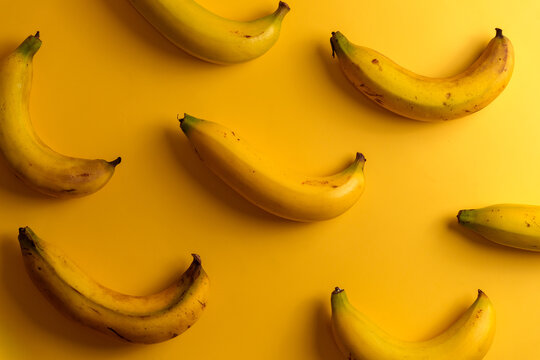 Top view of ripe yellow bananas pattern on solid yellow background