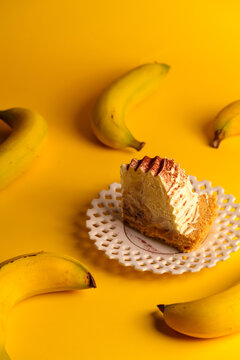 Minimalist food photography with a slice of tasty banoffee cake and fresh yellow bananas on bright background