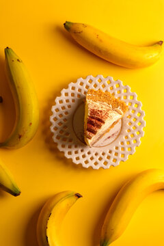 Creative flat lay of homemade banoffee cake on white lace plate surrounded by bananas