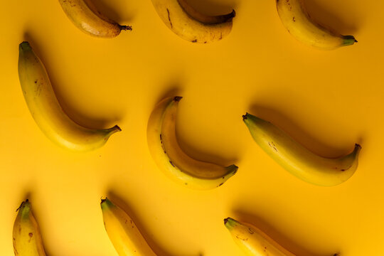 Top view of ripe yellow bananas pattern on solid yellow background