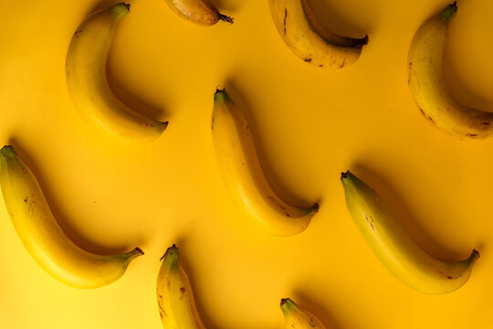 Top view of ripe yellow bananas pattern on solid yellow background