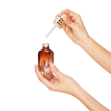 Clipping path, Hands holding glass dropper bottle and using pipette with liquid serum isolated on white background for skincare and cosmetic concept.