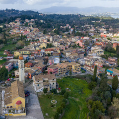 Fototapeta premium Aerial drone view of Potamos village, Saint Barbaros church tower, traditional architecture, green landscape near Corfu Town, Ionian Islands, Greece
