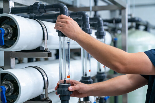 Industrial worker checks flow meter on reverse osmosis water purification system