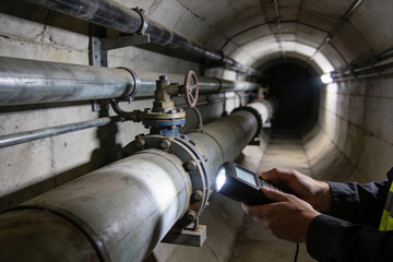 Industrial inspection of large pipes in a concrete tunnel with a flashlight and handheld device © Snide12