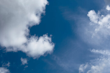 Obraz premium Blue sky with scattered white clouds. Soft cloud formations drift across an open atmosphere. Natural weather background for travel, nature, and design themes..