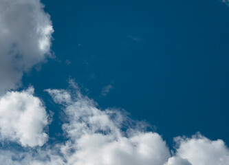 Fototapeta premium Blue sky with white cumulus clouds. Bright cloudscape with open daytime atmosphere. Natural weather background for design, travel, and environment use..