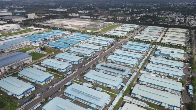 Aerial view of rows of blue-roofed industrial warehouses and factory buildings in a large manufacturing complex in An Phuoc, Dong Nai, Vietnam.