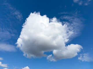 Obraz premium Large white cumulus cloud in a blue sky. Bright cloudscape with open daylight atmosphere. Natural weather background for travel, environment, and design..