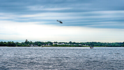 Fototapeta premium Helicopter flying overhead of a speedboat under a stormy sky.