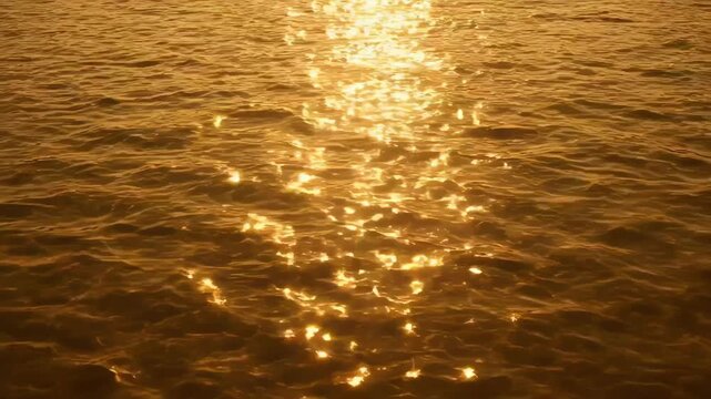 Shimmering golden sunlight creates a sparkling path across calm ocean waves, capturing the serene beauty of water and light during golden hour.