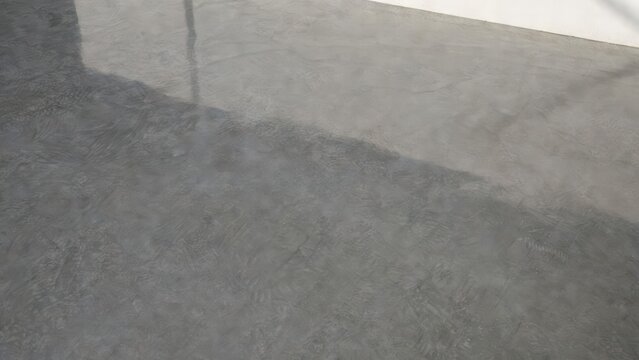 Textured concrete floor with subtle shadows and a clean white wall in the background