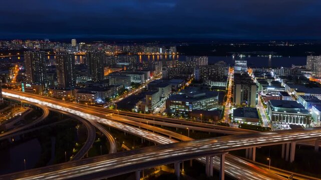 A cinematic aerial drone shot of a dense modern city at dusk, resembling New York City. Skyscrapers glow with warm office lights