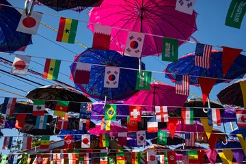 A vibrant display of colorful umbrellas suspended overhead on Isla Bastimentos, creating a lively canopy above a tropical street scene.  © cris