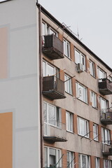 Fototapeta premium Vertical Weathered Concrete Apartment Building Facade with Rows of Windows and Air Conditioning Units Urban Residential Architecture Upward View