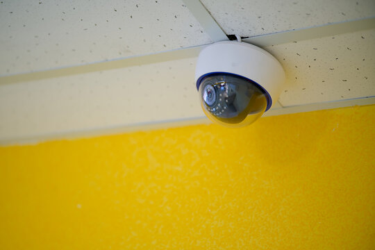 Modern rotating security camera installed on a drop ceiling inside a public building. Equipment for monitoring, video surveillance and property protection. Photo