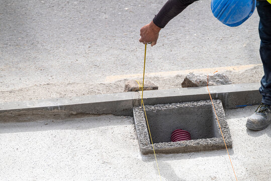 A builder using a guide line for precise alignment of a new manhole