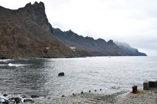 Stone jetty and rocky shoreline overlooking the steep volcanic mountains and Atlantic Ocean in Anaga Rural Park near Taganana, Tenerife, Canary Islands