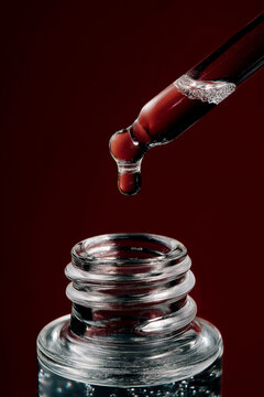 A close macro of pipette and liquid droplet above skincare bottle. Beauty treatment concept with sleek luxury presentation.