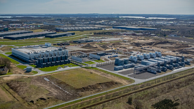 Large-scale data center campus with computing facilities  energy supply systems and advanced cooling infrastructure  undergoing expansion with visible construction areas, earthworks.