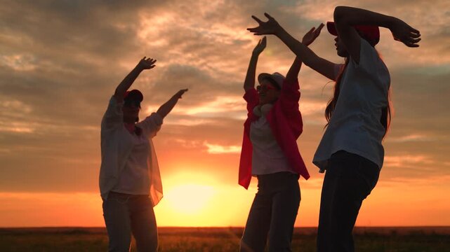 Youth party, dancing, group happy people raising their hands to sky in evening. People dancing to music, raising hands, outdoor party. People, holiday, picnic cheerful dancing nature. Youth party. Sun