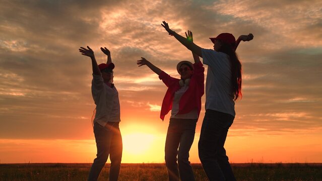 Youth party, dancing, group happy people raising their hands to sky in evening. People dancing to music, raising hands, outdoor party. People, holiday, picnic cheerful dancing nature. Youth party. Sun