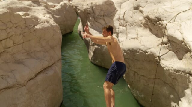 Slow Motion Male Tourist Jumping into Wadi Bani Khalid, Cinematic Cliff Jump in Omani Desert Oasis