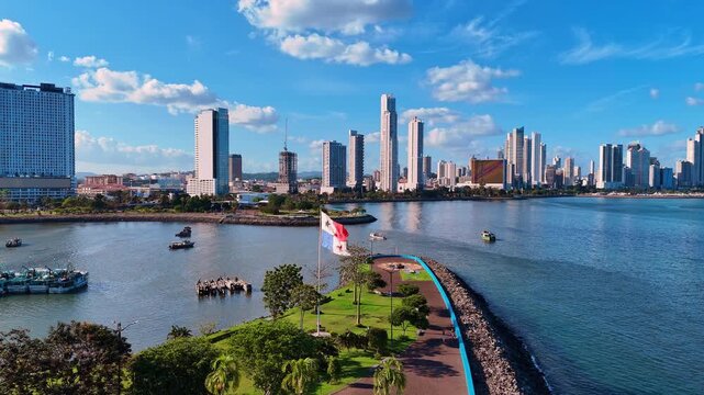 Panama flag on the pole flaps in the wind. Boat stand on the waterscape around the pier. Beautiful high-rise buildings in the backdrop.