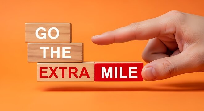 Hand pushing wooden block saying go the extra mile