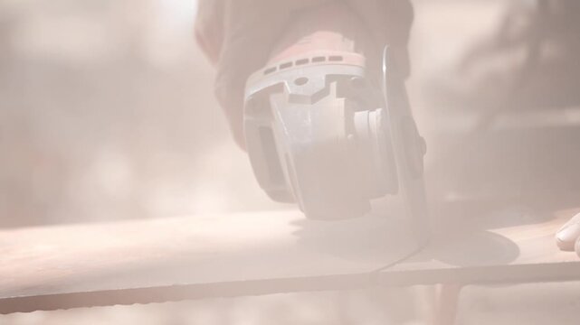 Close-up of a hand using an angle grinder to cut metal, sparks blurred in warm light, showing power tools, construction work, precision cutting, and industrial craftsmanship.