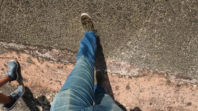 man dressed in jeans and sneakers walking on a stone path inside an old fort in san juan puerto rico looking down pov point of view