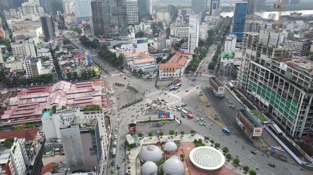 Aerial view of a busy city intersection with white domes and heavy traffic surrounded by urban buildings in Ho Chi Minh City, Ho Chi Minh, Vietnam.